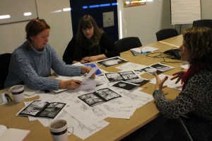 Paper-covered table. Kathy explains to Cathy what she wants, while Gill looks on